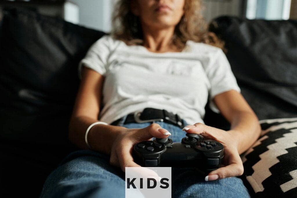 A woman relaxing on a sofa playing video games at home, focusing on a controller.