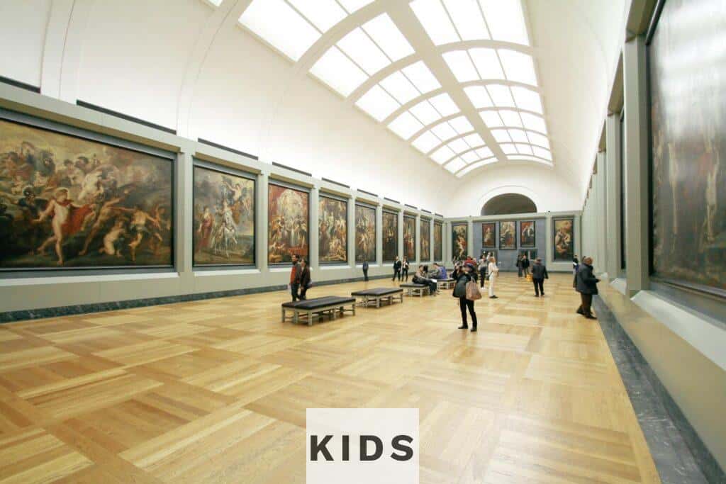 A wide view of a museum hall showcasing famous paintings and visitors exploring the art.