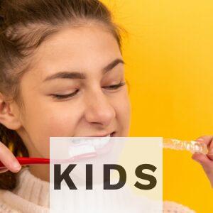 smiling girl in white sweater holding red and white toothbrush