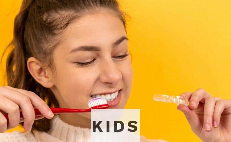 smiling girl in white sweater holding red and white toothbrush