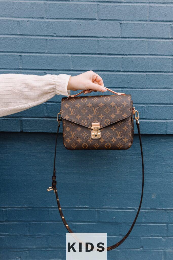 person holding brown leather sling bag