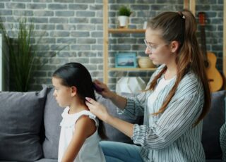 Madre revisando el pelo de su hija para detectar piojos en niños